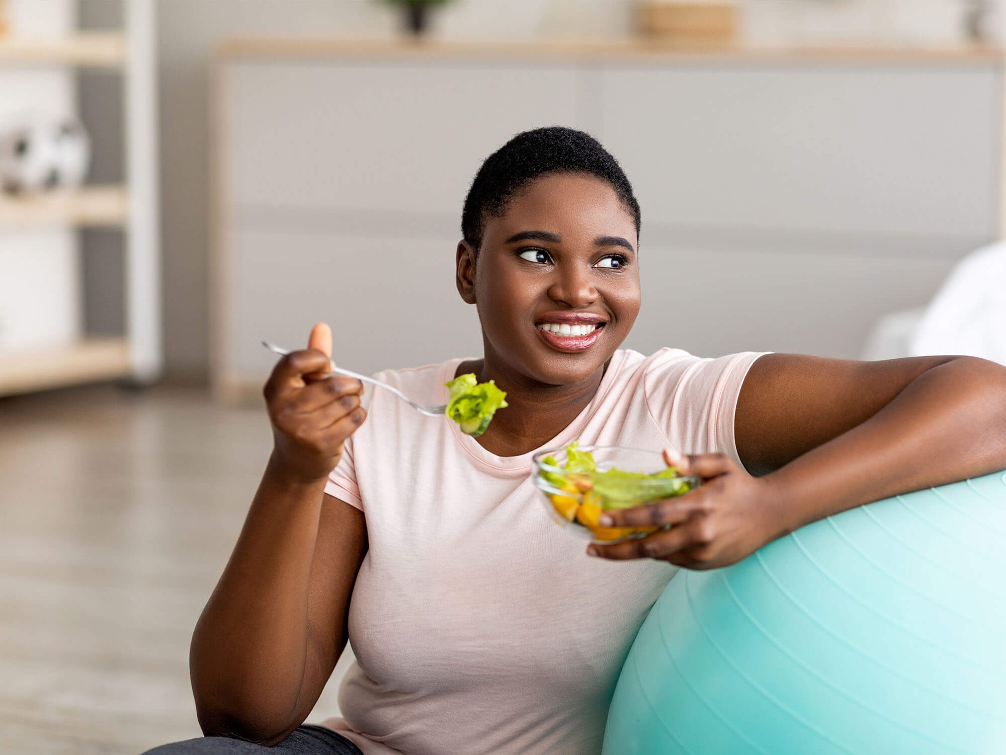 Woman eating healthy with an exercise ball